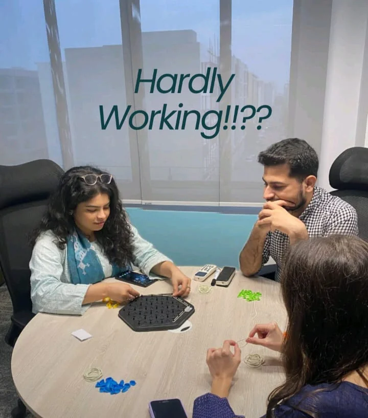 Behind the scenes: teammates playing a board game around a table, captioned 